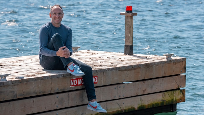 Doug Berger pose sur un quai. Il tient sa jambe droite au niveau de la cheville.