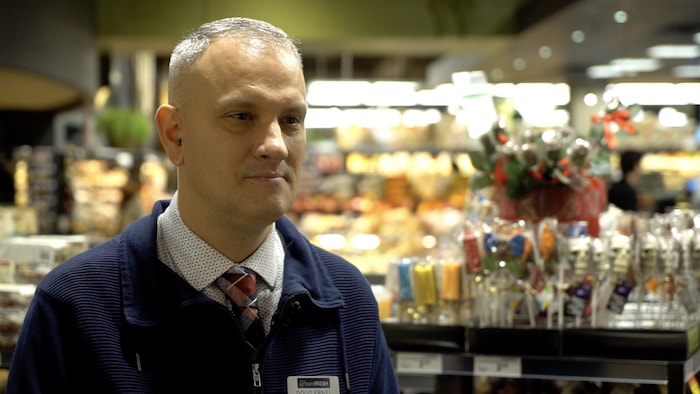 Un homme donne une entrevue dans un supermarché.