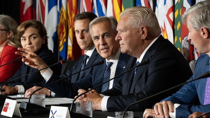 Mark Carney qui regarde Doug Ford durant une conférence de presse à Charlottetown le 23 juillet 2026.