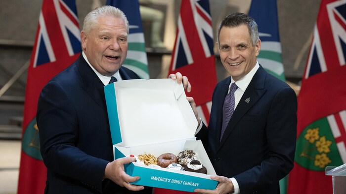 Le premier ministre Doug Ford et le maire d'Ottawa, Mark Sutcliffe, posent avec une boîte de beignes.