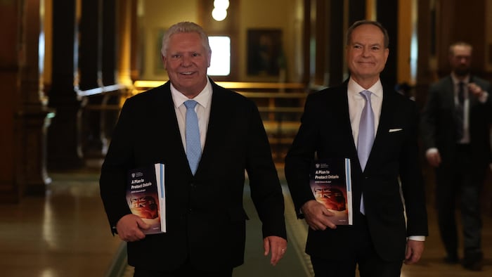 Le premier ministre ontarien, Doug Ford, et son ministre des Finances Peter Bethlenfalvy arrivent en Chambre à Toronto, budget à la main, le 15 mai 2025.