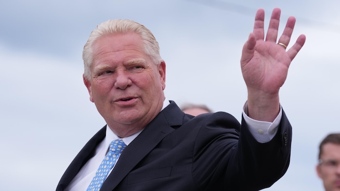 Doug Ford salue d’une main à son arrivée sur un chantier de Hamilton le 24 août 2026.
