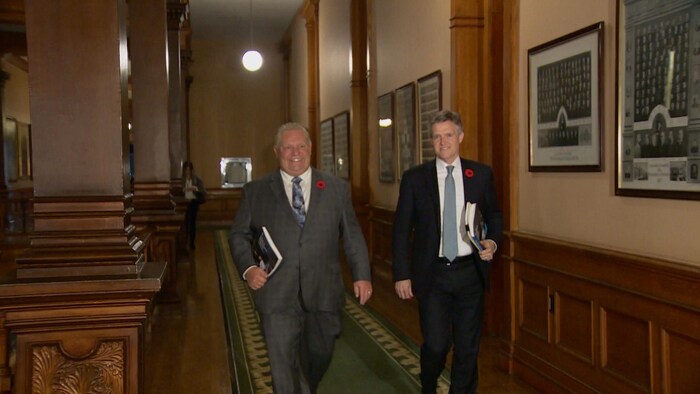 Deux hommes marchent dans les couloirs de l'assemblée législative.