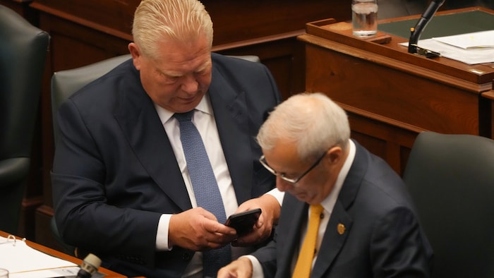 Les deux hommes sont assis en Chambre et regardent leurs cellulaires.