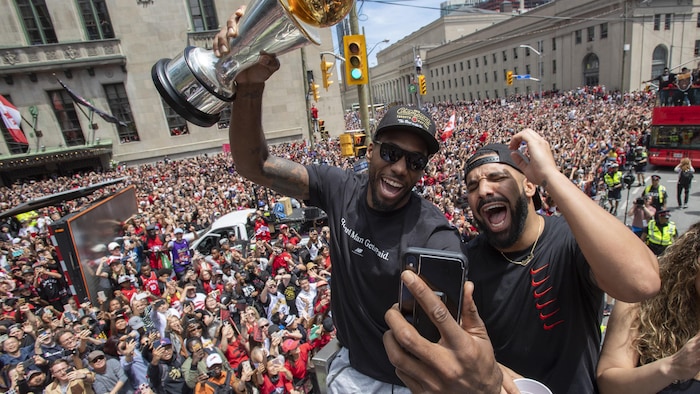 Kawhi Leonard brandit son trophée de joueur par excellence et célèbre la victoire avec Drake lors du défilé des champions de Toronto 2019, le lundi 17 juin 2019.