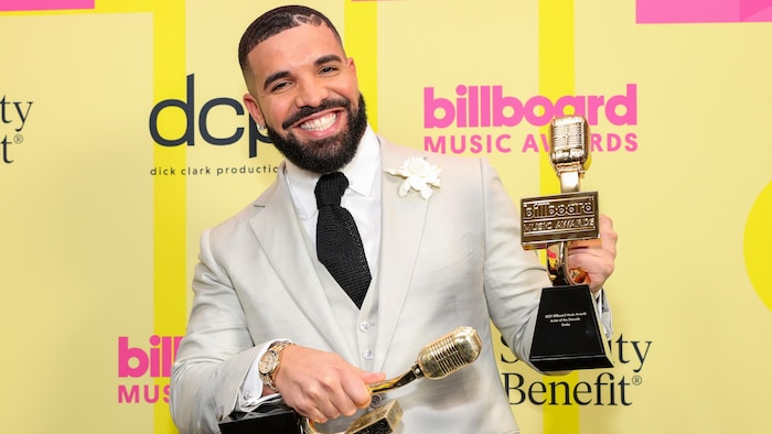 Le rappeur Drake tient deux trophées lors d'un gala de remise de prix.