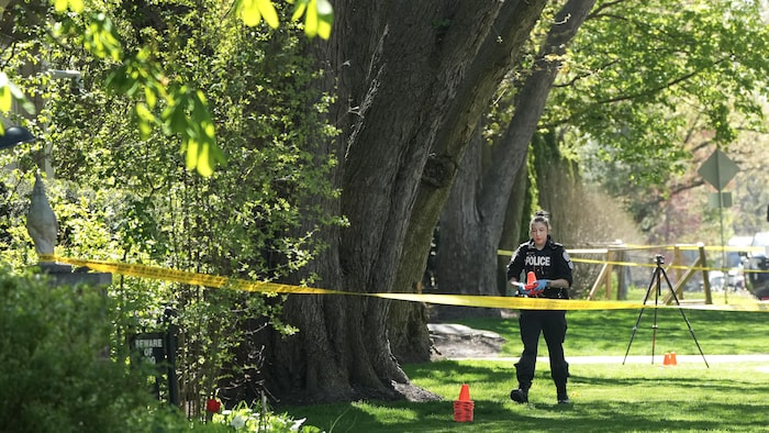 Une policière ramasse des cônes près du manoir de Drake à Toronto, le 7 mai 2024.