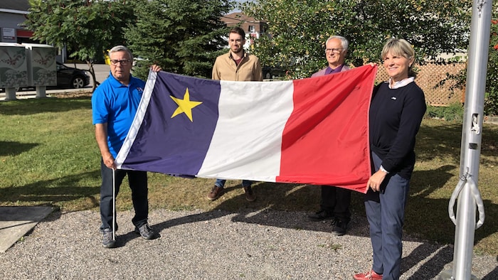 Quatre personnes tiennent un drapeau. 