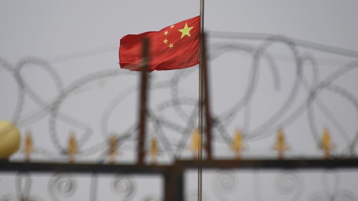 Des barbelés devant un drapeau de la Chine. 