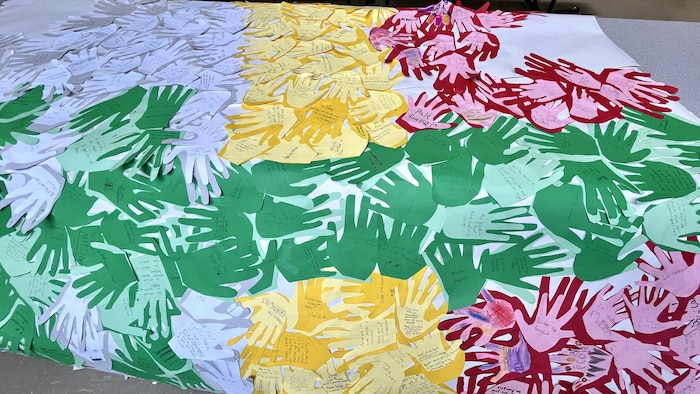Un drapeau franco-manitobain est composé de mains en papier. 