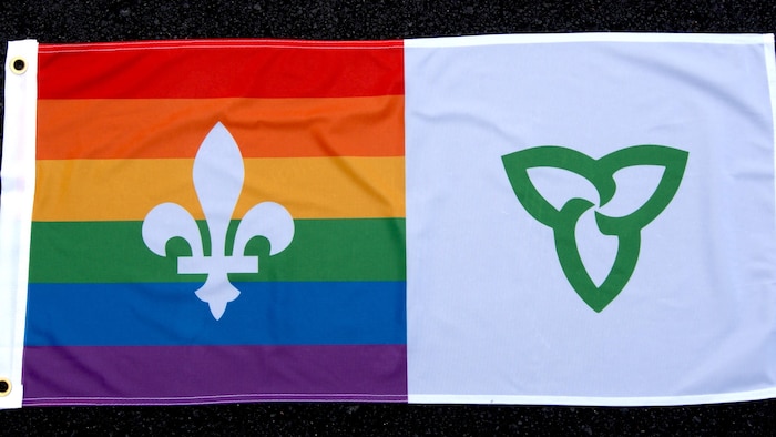 Un drapeau dont la moitié est le drapeau franco-ontarien, l'autre celui de la Fierté LGBTQ+. 