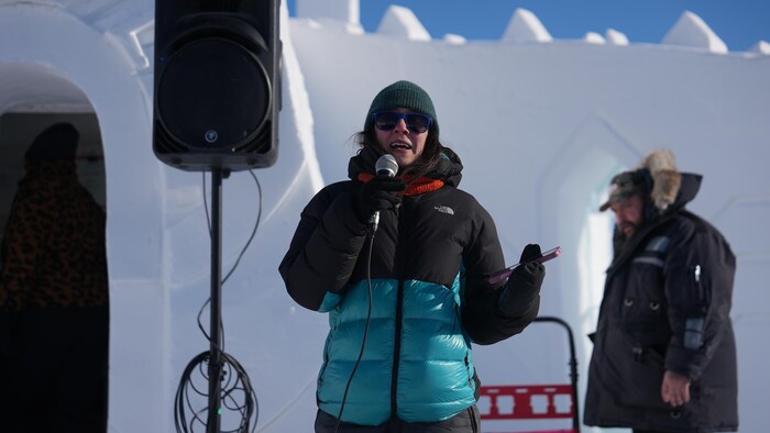 Audrey Fournier, un micro à la main dans un décor extérieur hivernal.