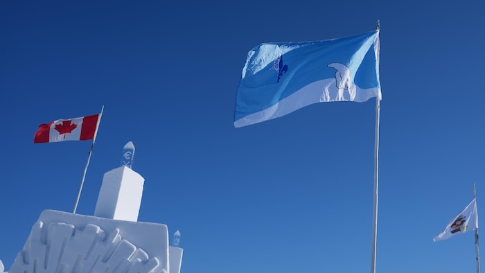 Le drapeau franco-ténois flotte au milieu d'autres drapeaux au château de neige de Yellowknife.