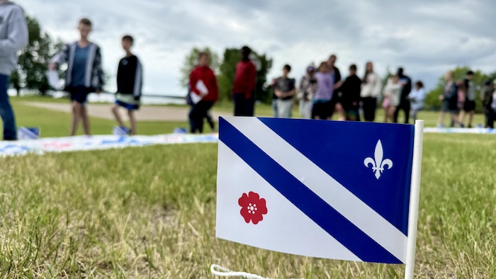 Le drapeau franco-albertain devant de jeunes francophones de la région de Saint-Paul, Alberta.