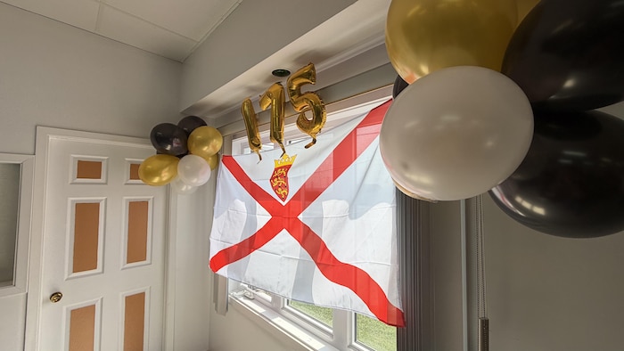 Le drapeau de Jersey est accroché devant la fenêtre, entouré de ballons festifs.
