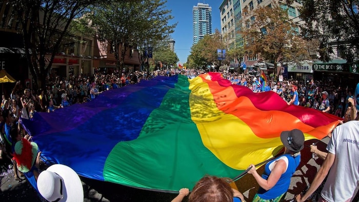 Un immense drapeau de la fierté est porté dans les rues du quartier West End à Vancouver lors d'un défilé. 