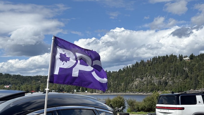 Un drapeau violet marqué des lettres « PPC » et d'une feuille d'érable est fixé à une voiture.