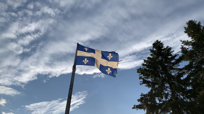 Le drapeau du Québec sous un ciel nuageux.