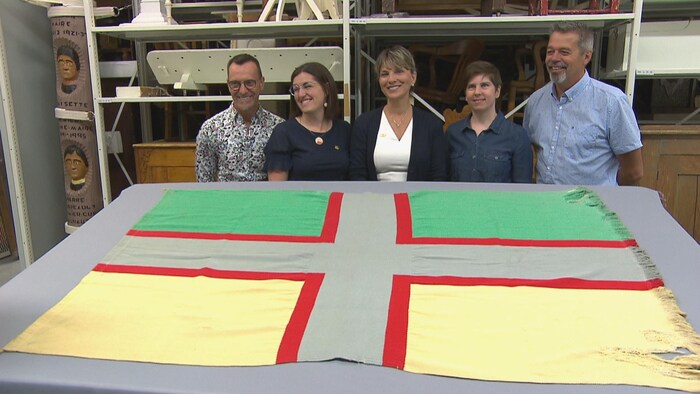 Josée Néron et des représentants de la Pulperie derrière le drapeau du Saguenay-Lac-Saint-Jean
