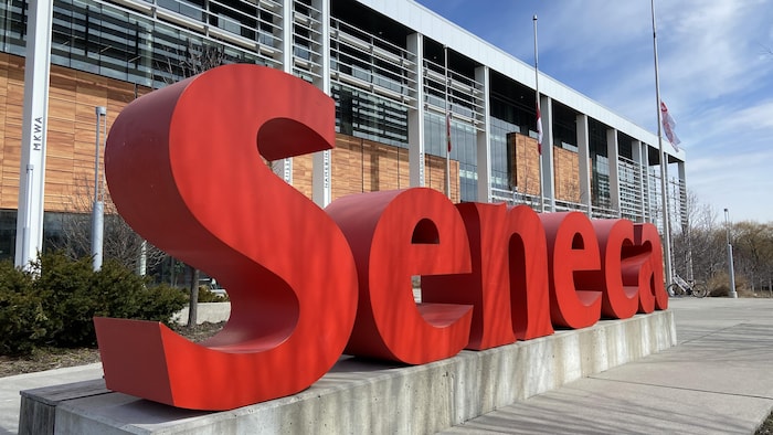 Le logo du collège devant l'établissement, ainsi que des drapeaux en berne. 
