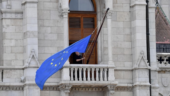 Un homme hisse le drapeau de l'UE sur le parlement  hongrois.