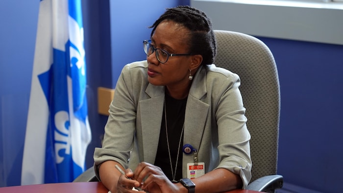 Assise près d'un drapeau du Québec, Omobola Sobanjo regarde à sa droite.