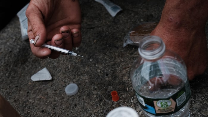 Une personne s'injecte une drogue dans la rue.