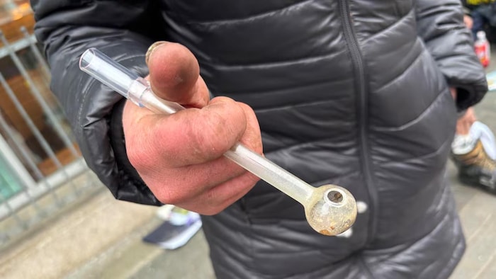 Un homme tient une pipe de verre utilisée pour fumer du fentanyl au centre-ville.