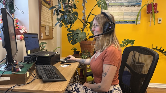 Une femme avec un casque d'écoute est assise à un poste de travail.