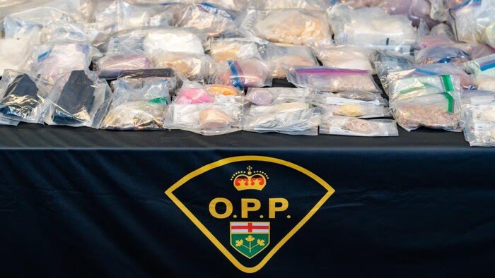 Plusieurs emballages contenant des substances présumées illicites sont disposés sur une table.