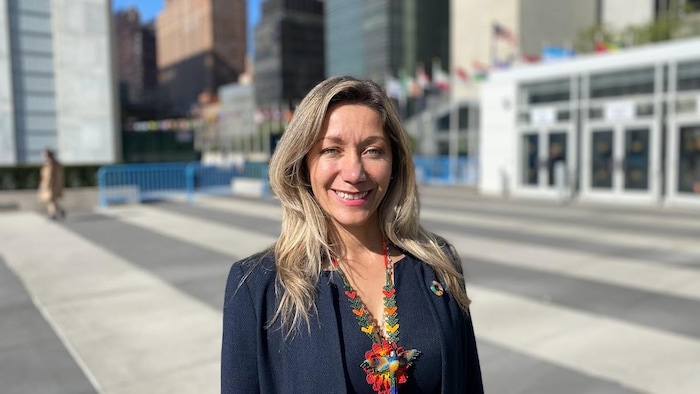 Elle sourit devant l'entrée de l'ONU à New York.