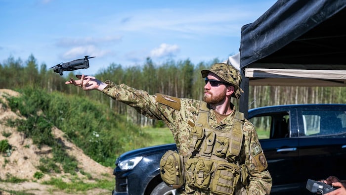 Un soldat lance un drone avec sa main.