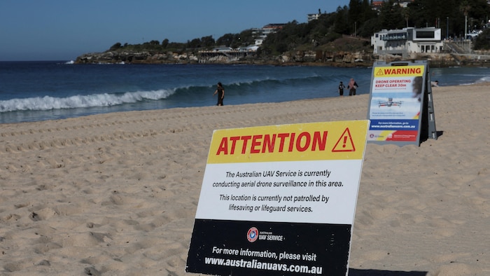 Deux enseignes plantées dans le sable, près de l'océan.