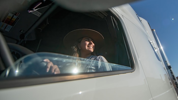 A woman behind the wheel of a truck, looking into the distance.