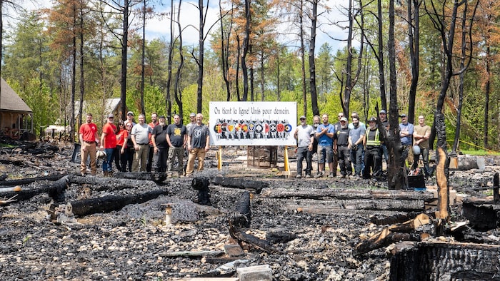 Sur le terrain de Bicolline, des participants brandissent une enseigne pour témoigner de leur soutien.