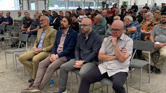 Une salle remplie de personnes assises sur des petites chaises.