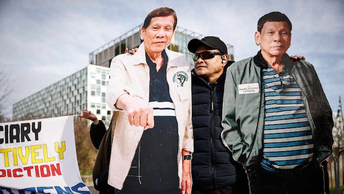 Une personne tient deux affiches en carton de Rodrigo Duterte.