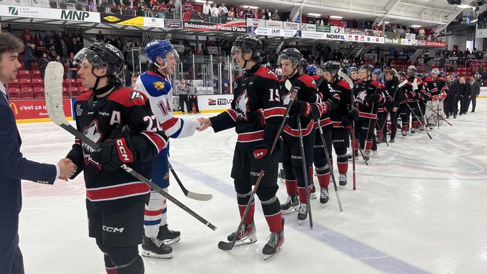 Dyllan Gill serre la main à un joueur des Huskies.