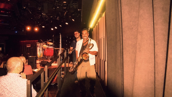 Deux hommes qui marchent avec leur instrument de musique hors de la scène.