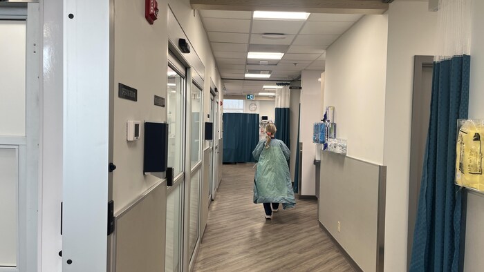 Une femme marche dans le couloir d'une clinique médicale. 
