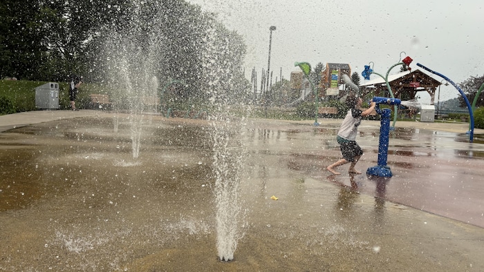 Un jeune garçon joue dans des jeux d'eau.
