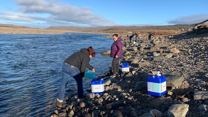 Des habitants d'Iqaluit remplissent des bidons d'eau à la rivière Sylvia Grinnell.