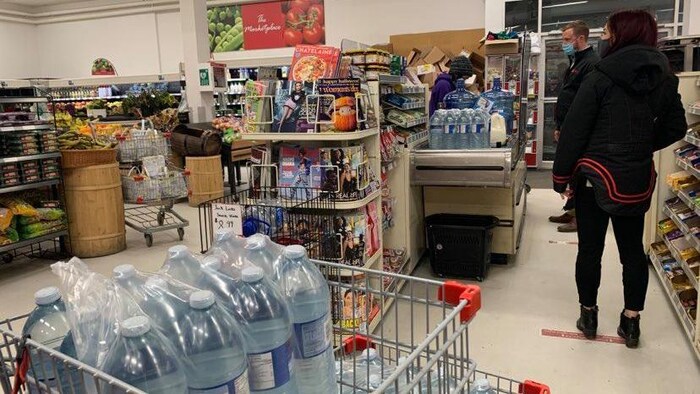 Des personnes achètent des bouteilles d'eau dans une épicerie d'Iqaluit.