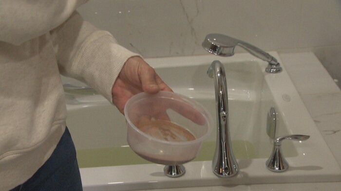 Les Gatinois découragés par l'eau colorée 2 Une femme tient un plat rempli d’eau jaune.