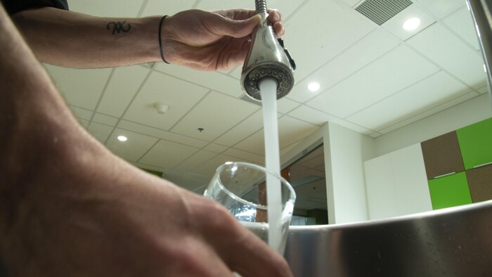 Quelqu'un se verse de l'eau dans un verre à partir d'un robinet,