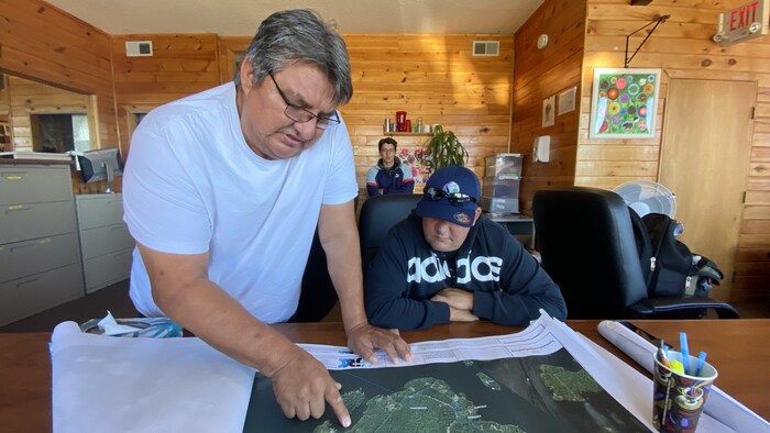 Deux hommes montrent sur une carte des emplacements