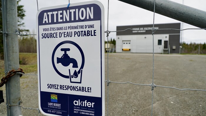 Une affiche devant une clôture indique une source d'eau potable.