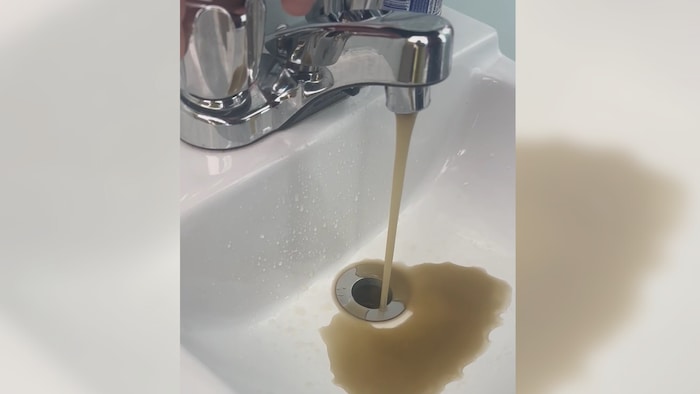 Un robinet crache de l'eau sale. 
