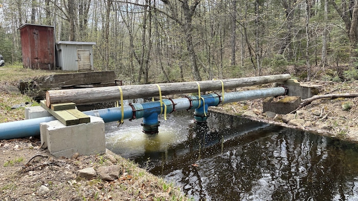 Un tuyau suspendue au dessus d'un canal d'eau.