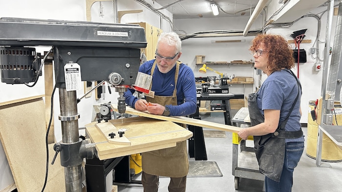 Deux personnes travaillent dans un atelier d'ébénisterie. 